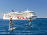 Couple on stand up paddle board in front of Pride of America