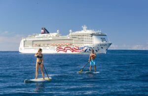 Couple on stand up paddle board in front of Pride of America